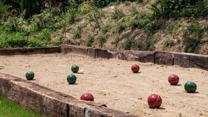 A croquet court with a wooden boundary and green and red balls.