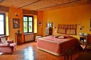 A bedroom with a large bed, a window with a view, a radiator, a cabinet, and a chair.