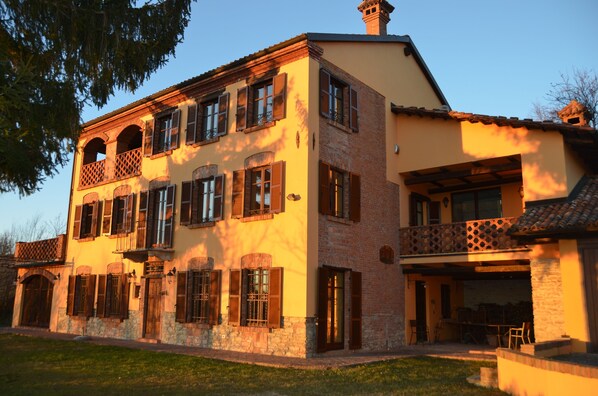 A two-story building with a balcony, stone foundation, and a flat roof.