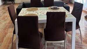 Uma área de refeições com mesa, cadeiras, televisão e sofá.