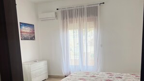Quarto com cama, cômoda, cadeira e um quadro na parede.