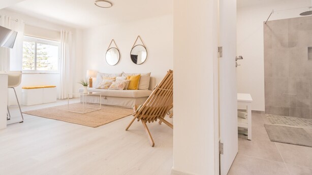 A modern living room with a sofa, a wooden chair, a small table, and a large window. - Parede Ocean (Parede)