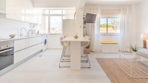 A modern kitchen with a dining area, large windows, and a view of the outdoors. - Parede Ocean (Parede)