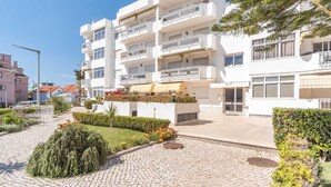 A multi-story residential building with balconies, a paved courtyard, and surrounding greenery. - Parede Ocean (Parede)