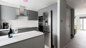 Una cocina moderna con gabinetes grises, electrodomésticos de acero inoxidable y encimera blanca.