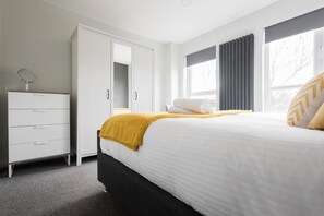 A bedroom with a bed, a wardrobe, a dresser, and a window with curtains. - Second Nest Waterloo (London)
