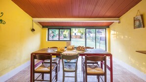 A dining area with a wooden table and chairs, a window with a view of the outdoors, and a yellow wall. - House in Tuscany immersed in greenery  (Foiano della Chiana)