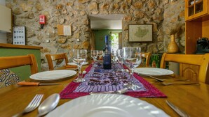 Una mesa de comedor dispuesta con platos, cubiertos y vasos, con una botella de licor en el centro.