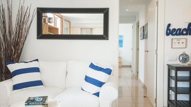 A modern living room with a white sofa, a small round table, and a mirror on the wall. - LOVELY POOL APARTMENT with PARKING 3 (Tossa de Mar)