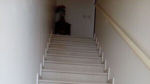 A staircase with white steps and a handrail, leading to a room with a dark-colored door and a vase with flowers. - 1 Bedroom Duplex with Balcony and Seaview (5-10 minutes form beach) (Alvor)