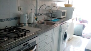 A kitchen with white cabinets, a gas stove, a microwave, a sink, and a washing machine. - 1 Bedroom Duplex with Balcony and Seaview (5-10 minutes form beach) (Alvor)