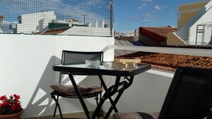 A terrace with a table and chairs, a potted plant, and a view of buildings under a clear sky. - 1 Bedroom Duplex with Balcony and Seaview (5-10 minutes form beach) (Alvor)