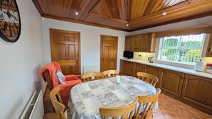 A cozy kitchen with wooden cabinets, a dining table with chairs, and a window with a view of greenery. - Charming 3 Bedroom, Self Catering in centre of Mid Ulster close to Cookstown (Rock Dungannon)