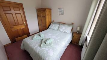 Une chambre à coucher avec un lit, une armoire en bois, une table de chevet avec une lampe et un tableau encadré au mur.