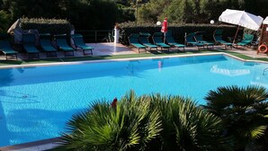 A swimming pool with multiple lounge chairs and umbrellas.