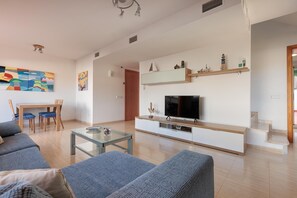 A modern living room with a sofa set, a TV, a coffee table, and a dining area with chairs.