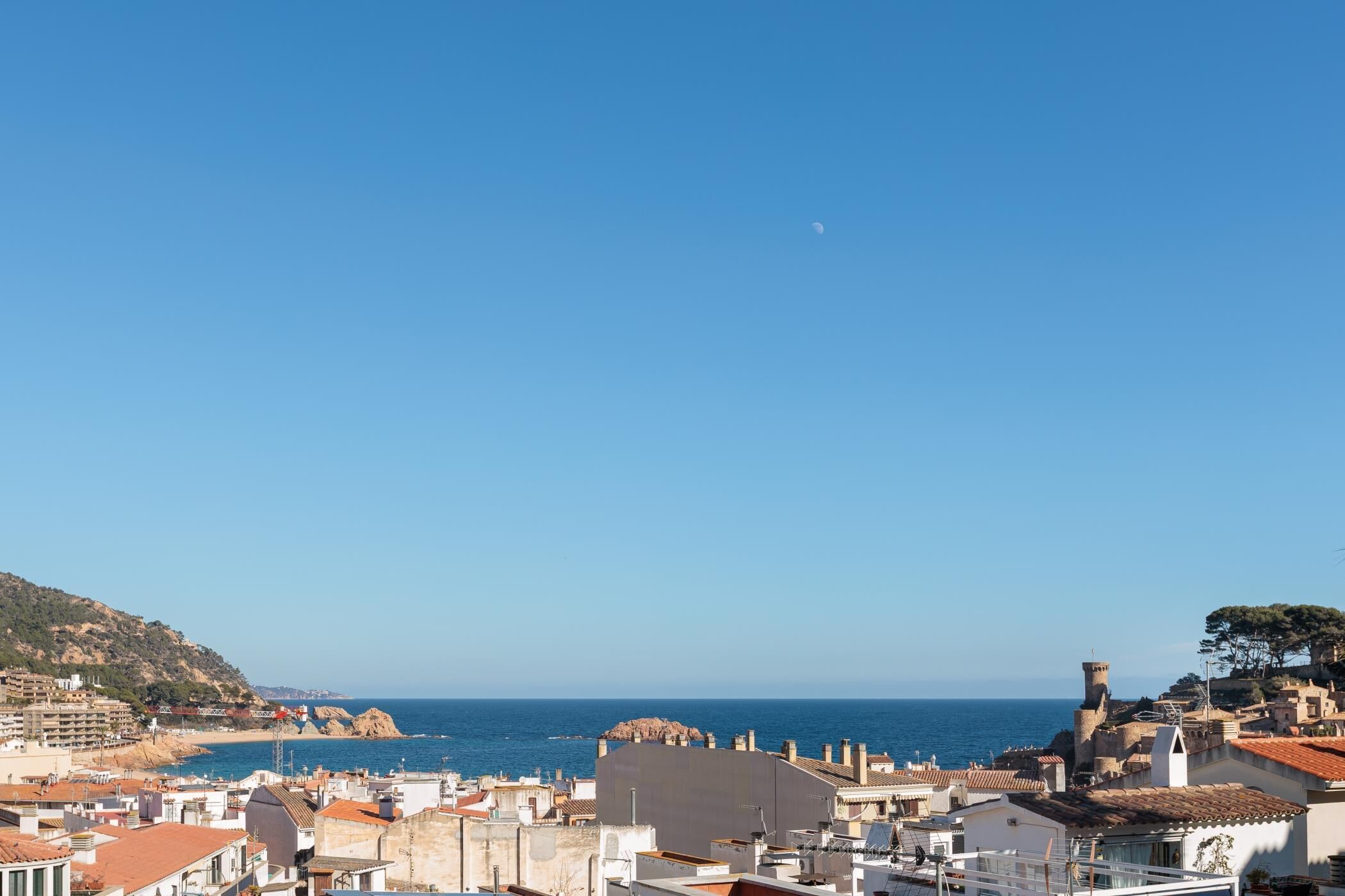 A coastal town with buildings, a clear sky, and the sea.