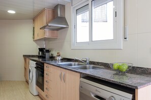 Une cuisine moderne équipée d’un lave-linge, d’un lave-vaisselle et d’une grande fenêtre.
