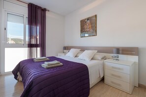 A bedroom with a bed, nightstands, a painting, and a view through a window.