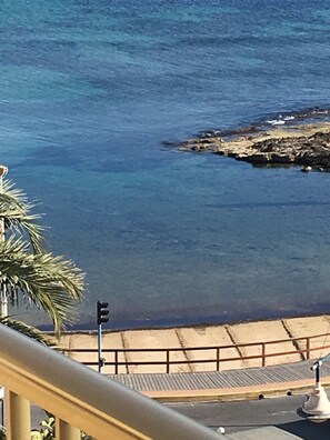 Une vue sur la côte, avec une eau d’un bleu limpide, un rivage rocheux et une promenade pavée.
