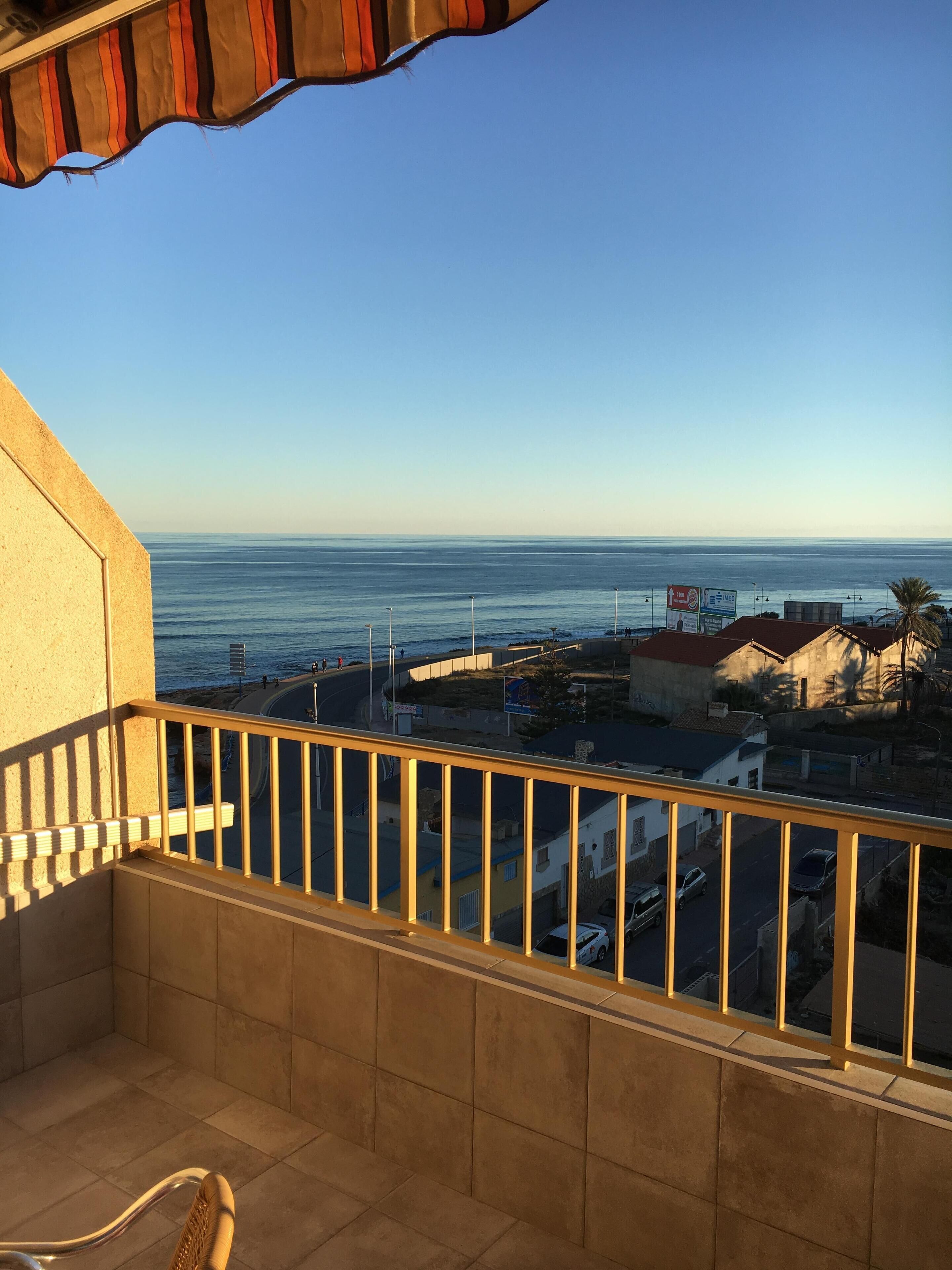 A balcony with a view of the sea and buildings.