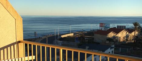 A balcony with a view of the sea and buildings.