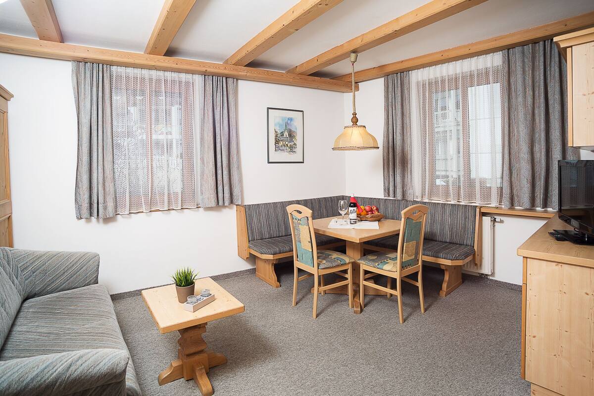 Une pièce chaleureuse avec un plafond en bois, une table à manger avec des chaises, un canapé et un téléviseur.