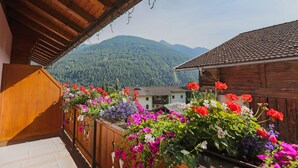 A wooden balcony with colorful flowers and a view of a mountain. - Panzl braü (Virgen)