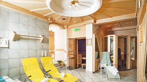 A sauna room with yellow chairs, a wooden ceiling, and a visible exit sign. - Panzl braü (Virgen)