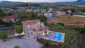 A large house with a swimming pool, surrounded by a fenced yard and a view of the countryside. - Hilltop Villa with Private Pool | Panoramic Views | Sea Turtle National Park.  (Zakynthos)