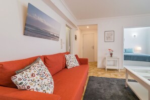 A living room with a red sofa, a small white table, and a grey rug.