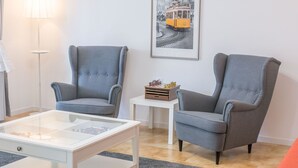 Ein modernes Wohnzimmer mit zwei grauen Sesseln, einem weißen Couchtisch und einem schwarz-weißen Foto in einem Rahmen an der Wand.