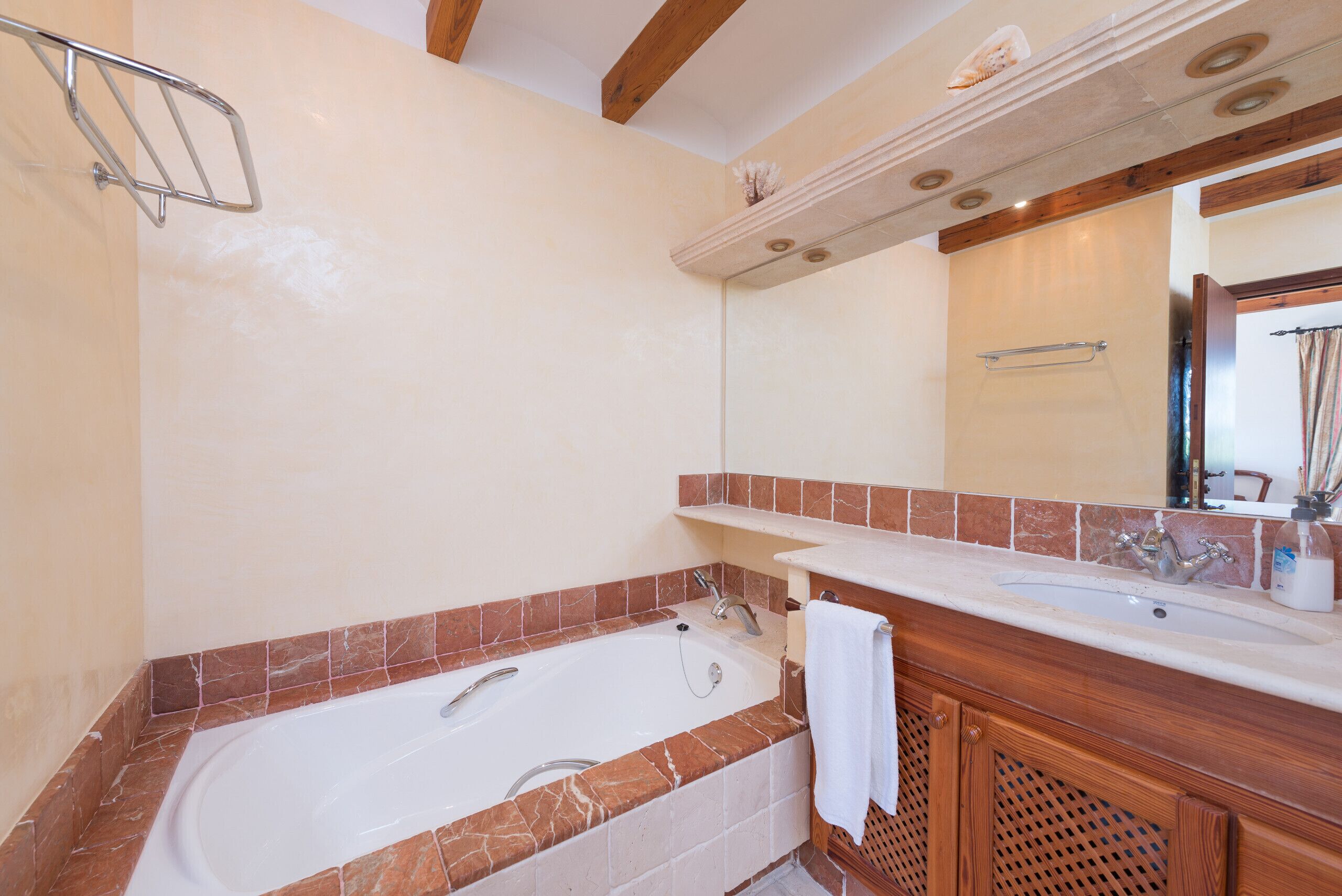 Un bagno con una vasca, un lavabo e un mobile contenitore con uno specchio.