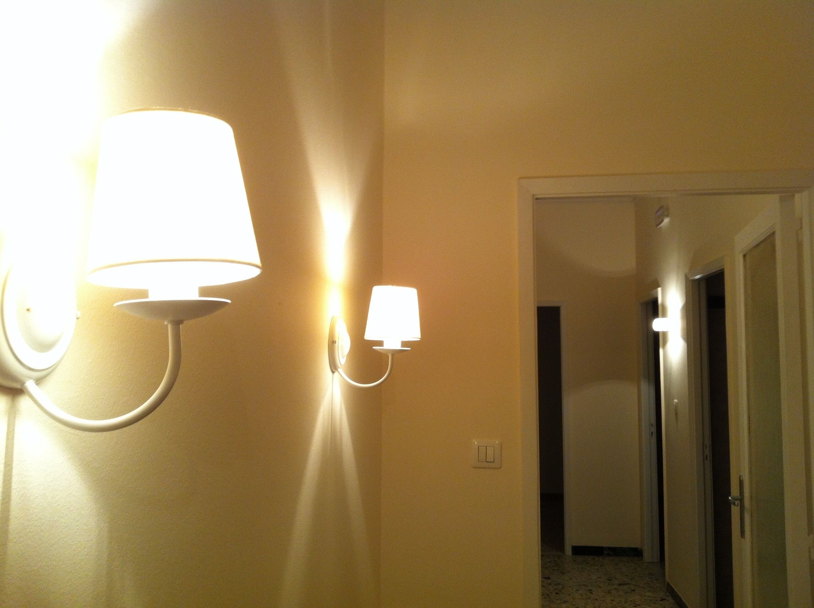 A hallway with two wall-mounted light fixtures and a door leading to another room.