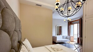 Ein modernes Schlafzimmer mit einem großen Bett, einem außergewöhnlichen Kronleuchter und Blick ins Zimmerinnere.