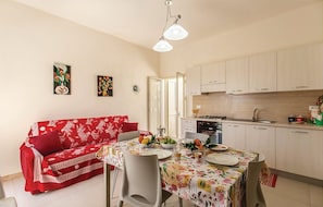 A compact living space with a dining area, kitchenette, and a red sofa.