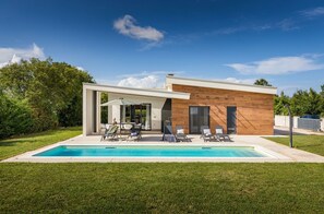 A modern house with a swimming pool, outdoor seating, and a wooden facade. - Villa Sama - Beautiful modern built villa with pool in Central Istria (Zminj)