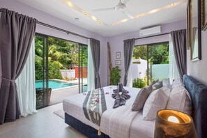 Un dormitorio con una cama grande, un ventilador de techo y vista a una piscina.