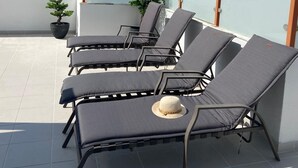 Une terrasse sur le toit avec des chaises longues, un pot de fleurs et une vue sur la mer.