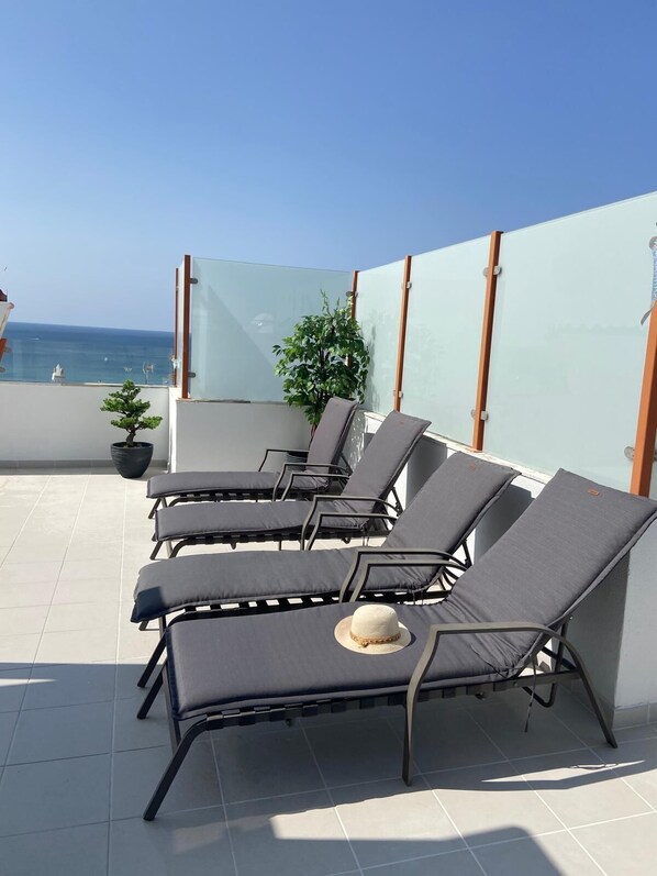 A rooftop terrace with sun loungers, a potted plant, and a view of the sea. - LUXURIOUS 4 ROOM APARTMENT - TERRACE 120M² - SEA VIEW - PRAIA DA ROCHA (Portimão)