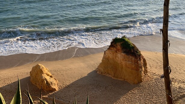 Une plage avec de gros rochers, une étendue de sable et l’océan.