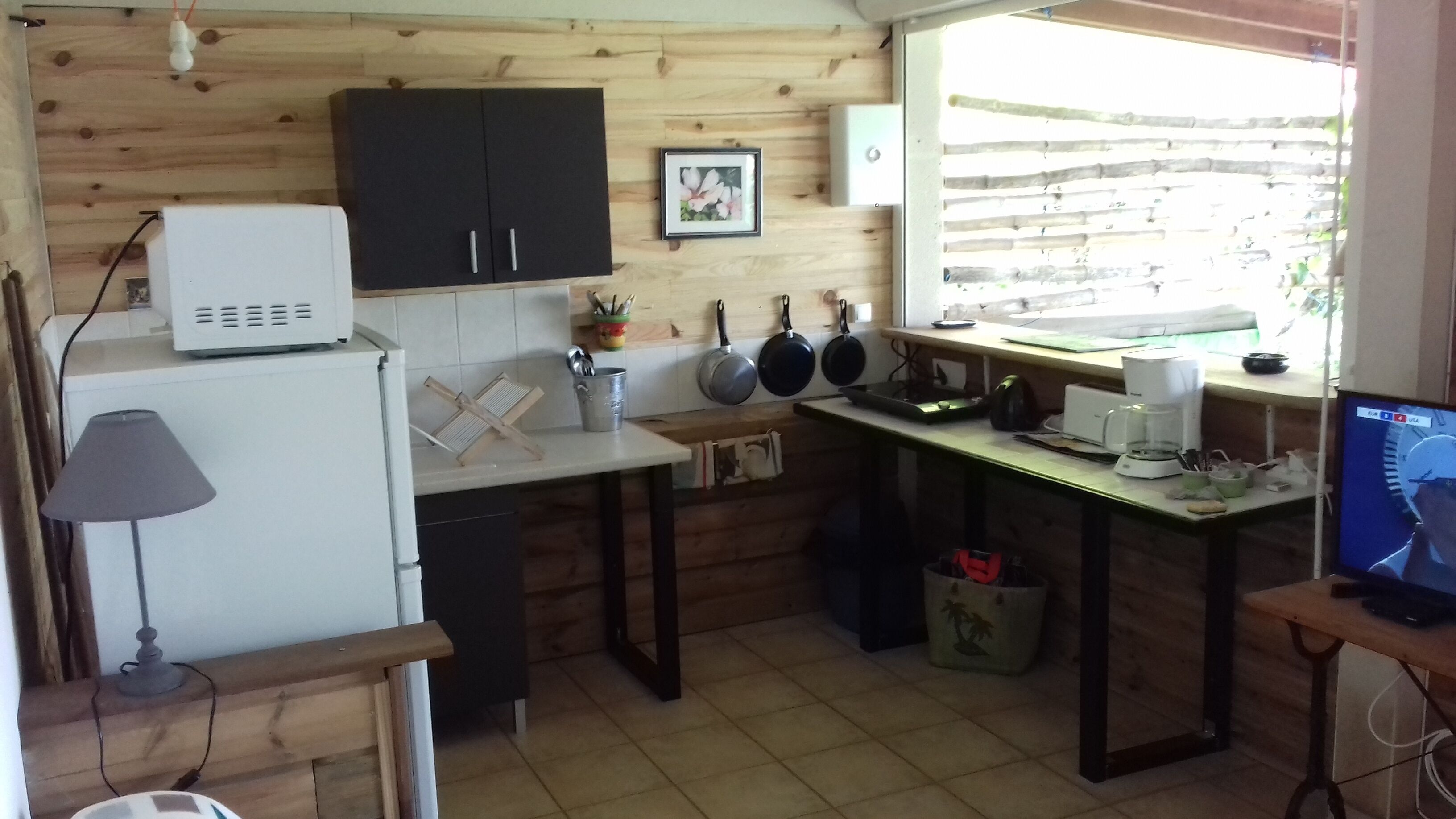 A compact kitchen with wooden cabinets, a white refrigerator, a small sink, and a window with a view of the outside.