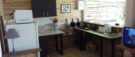 A compact kitchen with wooden cabinets, a white refrigerator, a small sink, and a window with a view of the outside.