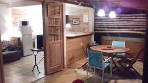 A compact kitchen with a refrigerator, a microwave, and a sink. There is a dining area with a round table and blue chairs. - Kay Zanndoli, sea view, pool, jacuzzi, garden (La Trinité)
