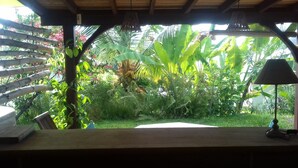 A covered outdoor area with a table and chairs, surrounded by lush greenery and a variety of plants. - Kay Zanndoli, sea view, pool, jacuzzi, garden (La Trinité)