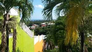 A view of a residential area with houses, palm trees, and a clear sky. - Kay Zanndoli, sea view, pool, jacuzzi, garden (La Trinité)