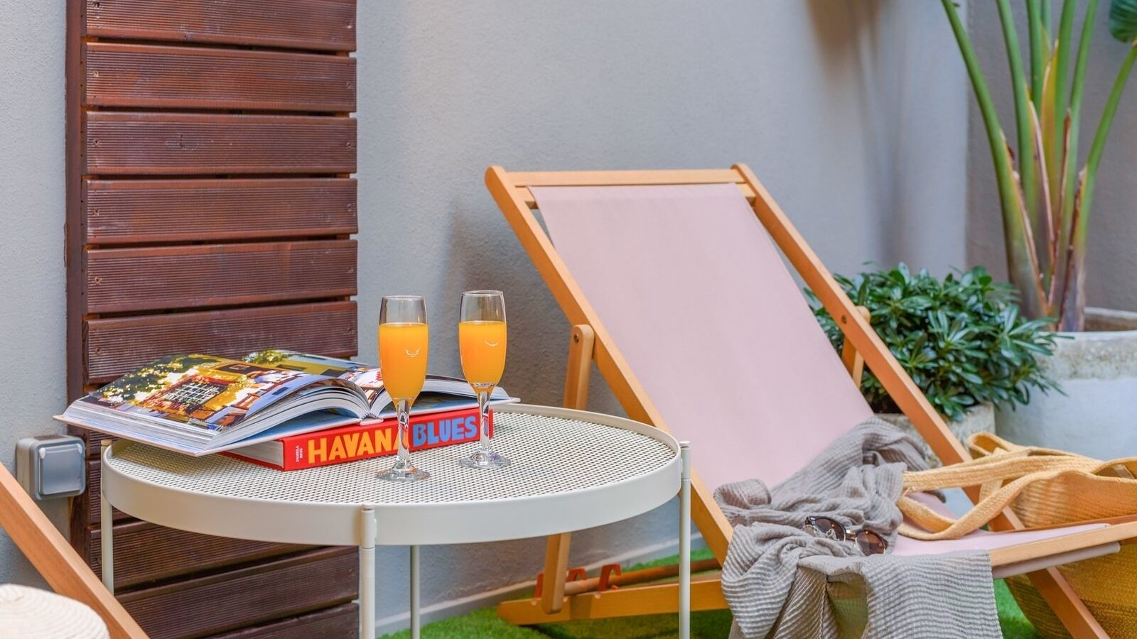 Ein kleiner runder Tisch mit einer Zeitschrift, zwei Orangensaftgläsern und einer Sonnenbrille.