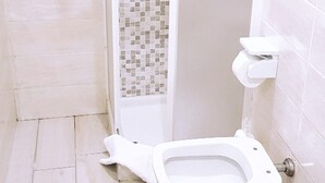Een badkamer met een wit toilet, een douche met mozaïektegels en een wastafel.