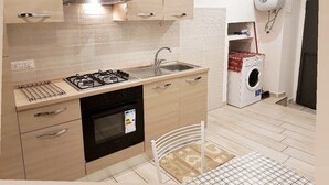 Een kleine keuken met een gasfornuis, spoelbak, oven en een wasmachine.