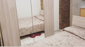 Een slaapkamer met een bed, een bakstenen muur en een witte inloopkast.